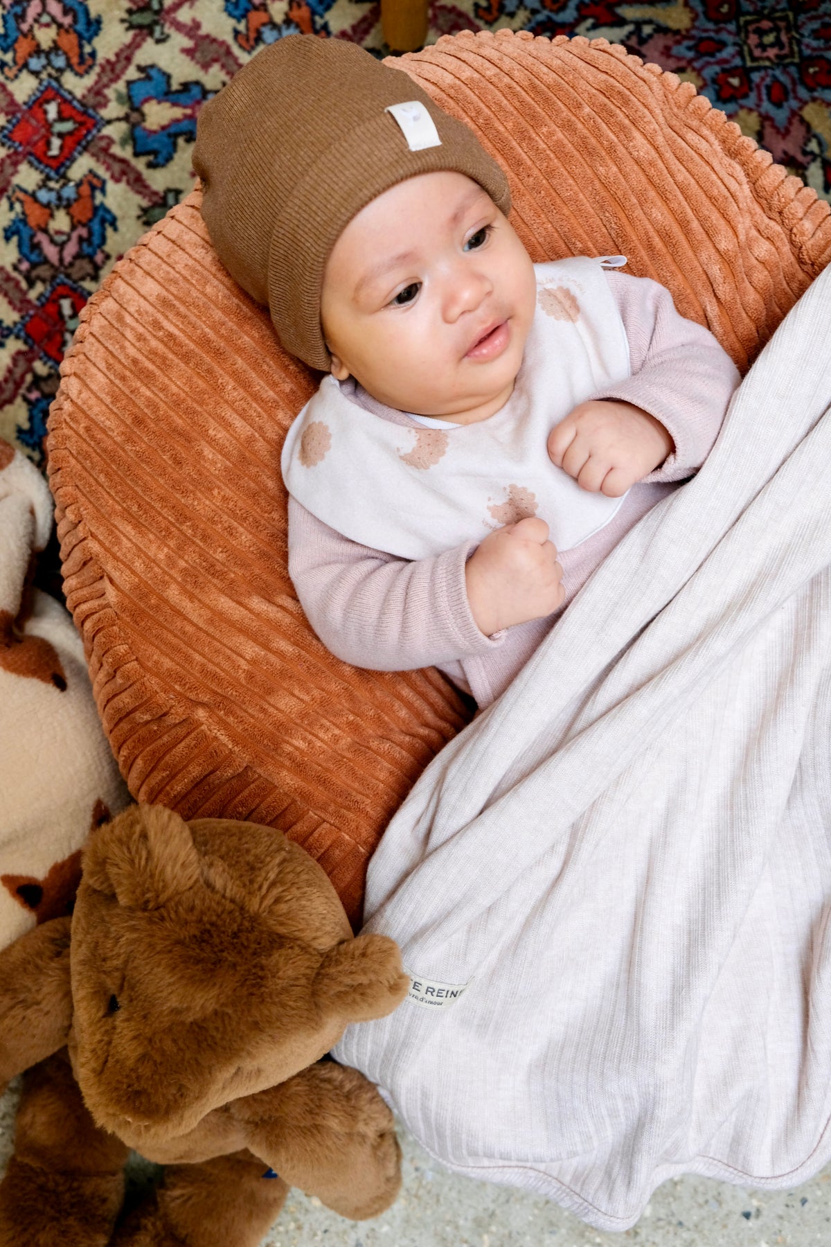 Bébé sur nid avec un bonnet de naissance et un bavoir 