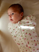 Bébé paisible dans une emmalloteuse à fleurs 