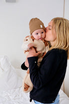 maman embrassant son bebe avec gigoteuse hiver friends et bonnet marron