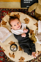bébé sourire sur nid friends avec parure bonnet bavoir de naissance