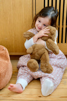 enfant fille portant sa peluche en gigoteuse à pieds guimauve