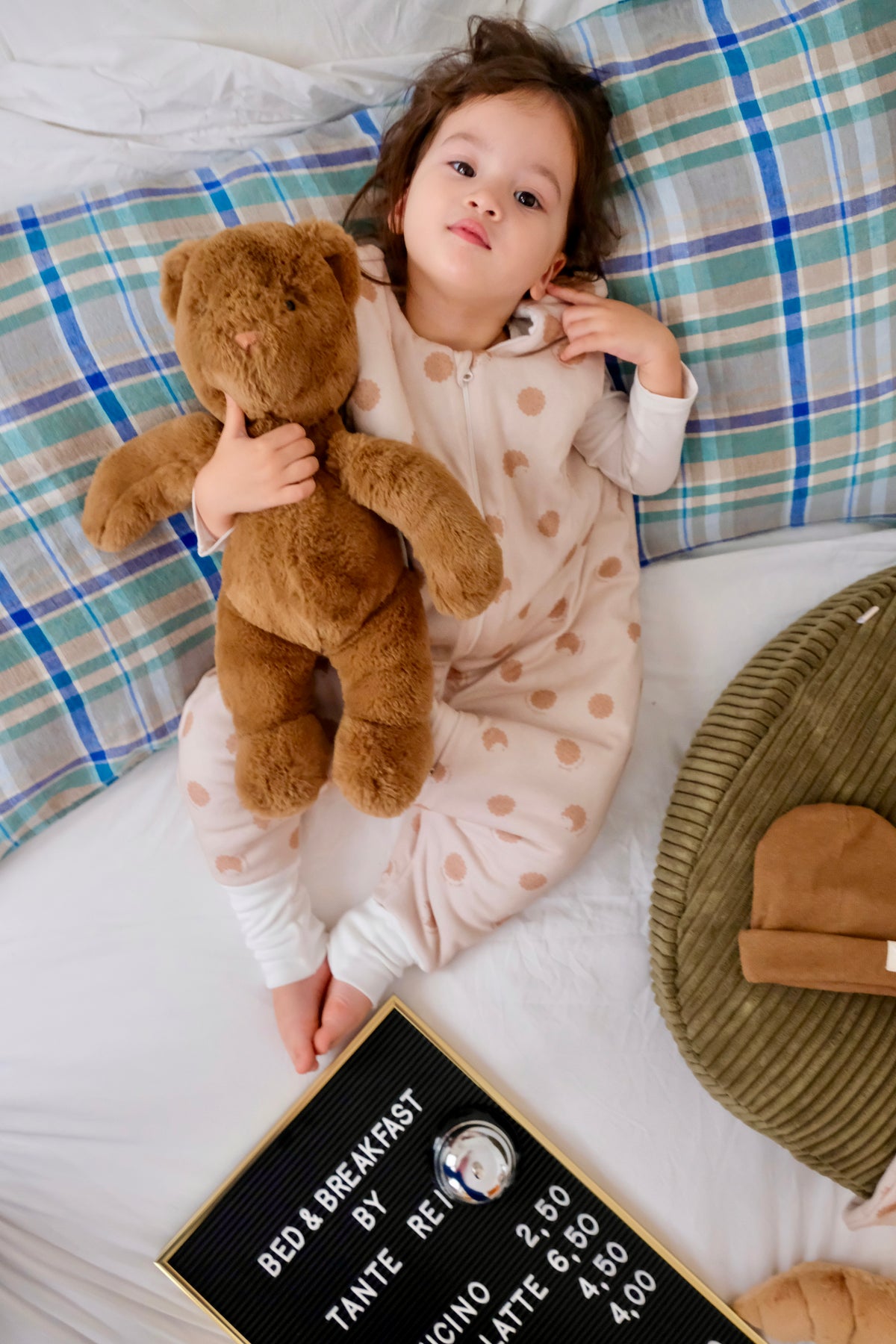 enfant portant une peluche sur un lit avec gigoteuse à pieds cookie