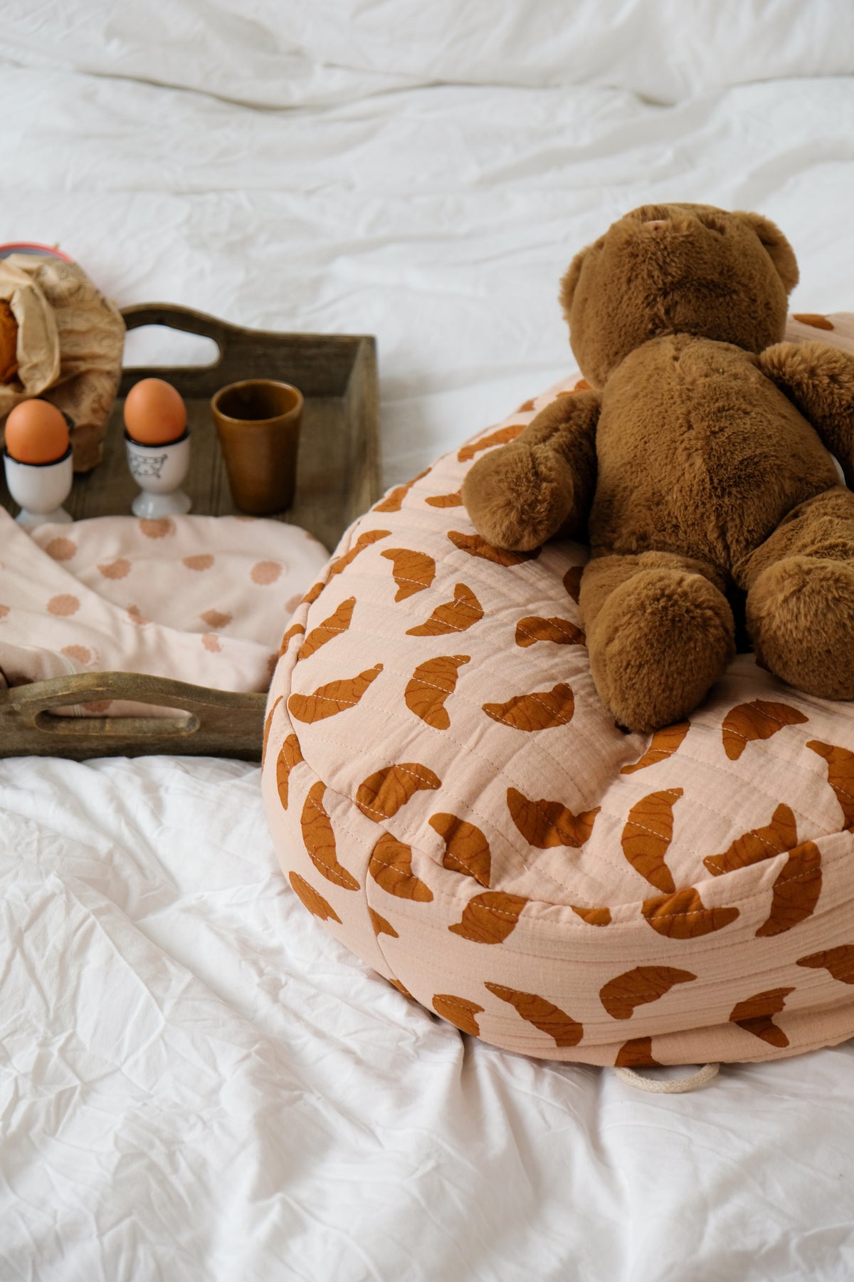 peluche ours sur un pouf nid bag croissant et oeufs à la coque