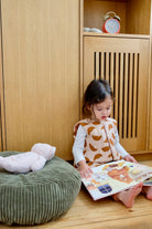 enfant fille lisant un livre dans sa chambre a cote d'un nid et d'une peluche